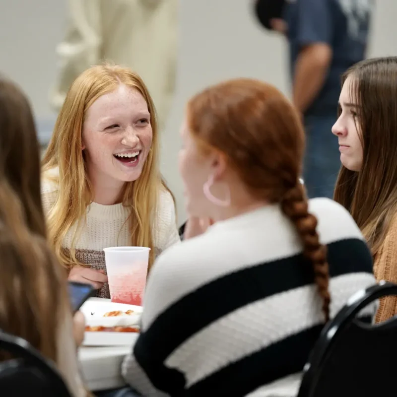 Students smiling while sitting at a table